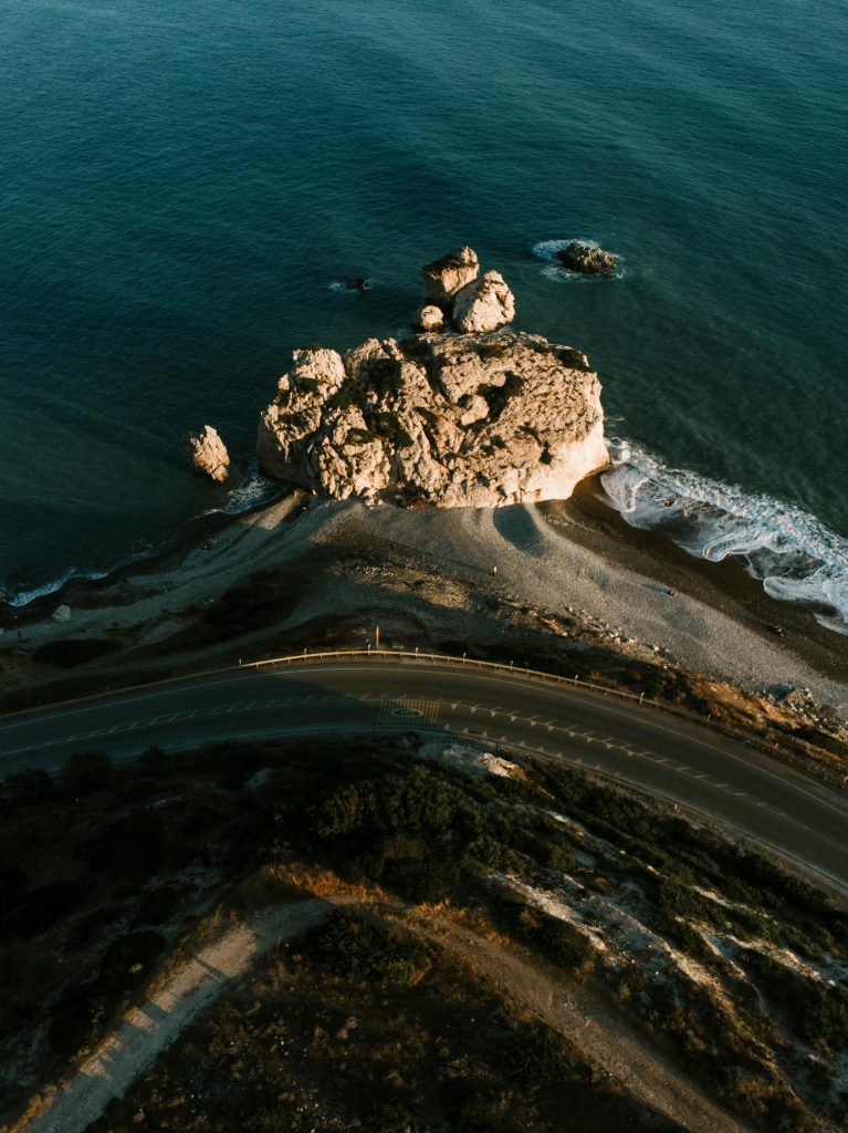 pexels photo 6190823 6190823 Aerial shot capturing a rocky coastline with a winding road in Paphos, Cyprus.
